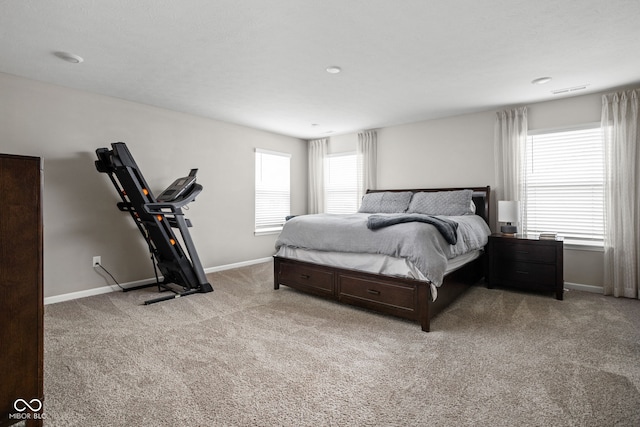 bedroom with baseboards, visible vents, and light carpet