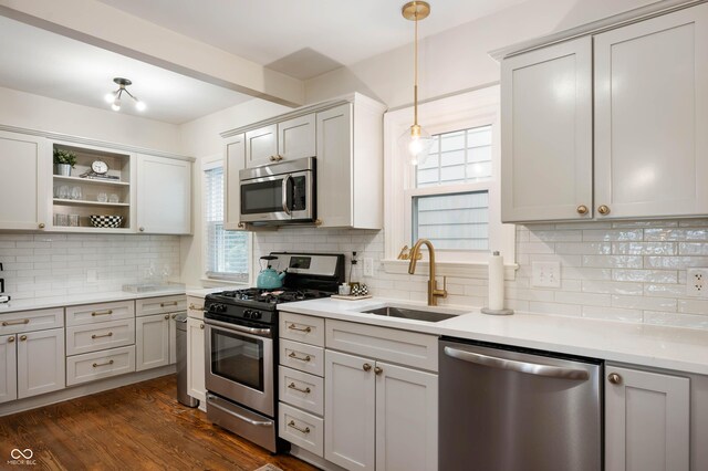 kitchen with appliances with stainless steel finishes, a sink, decorative backsplash, open shelves, and light countertops