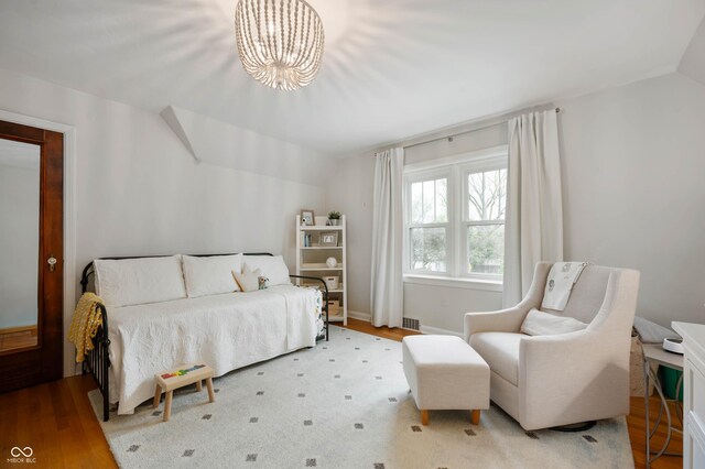 bedroom with vaulted ceiling, a chandelier, and wood finished floors