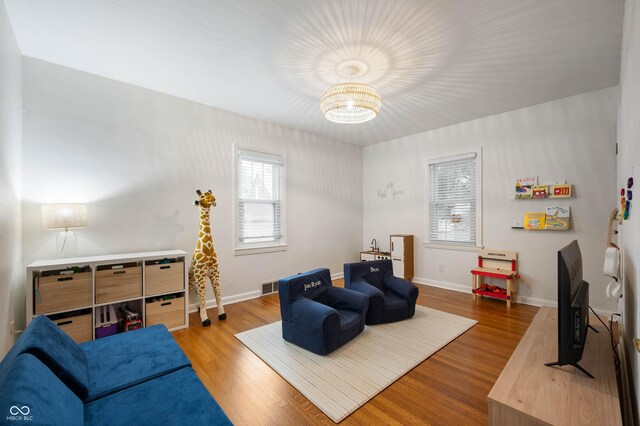 living area with wood finished floors, a chandelier, and baseboards