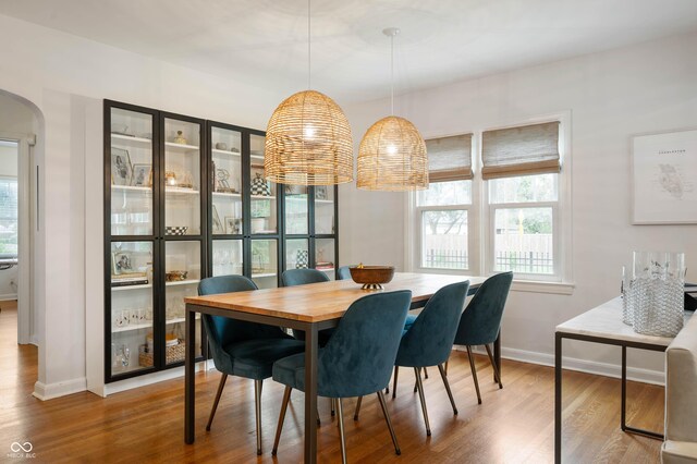 dining area featuring wood finished floors, baseboards, and arched walkways
