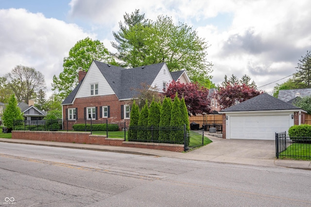 view of front of house with brick siding, a fenced front yard, a detached garage, and a chimney