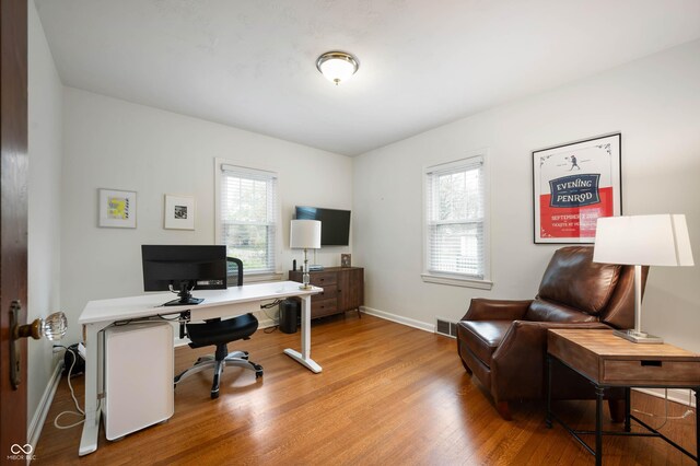 office space with healthy amount of natural light, light wood-style floors, and baseboards