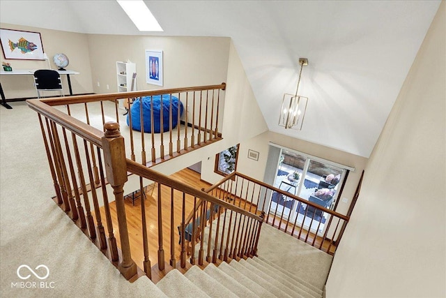 stairs featuring vaulted ceiling with skylight, carpet floors, and a chandelier