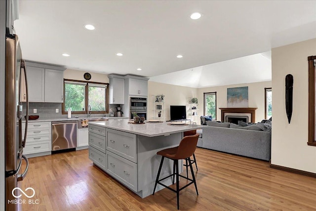 kitchen featuring gray cabinetry, appliances with stainless steel finishes, a sink, and open floor plan