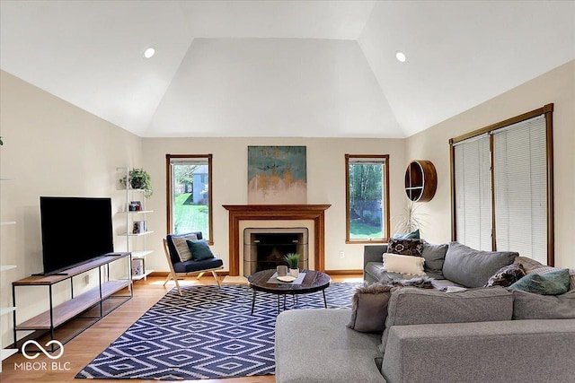 living room featuring light wood-style floors, high vaulted ceiling, recessed lighting, and a fireplace with flush hearth