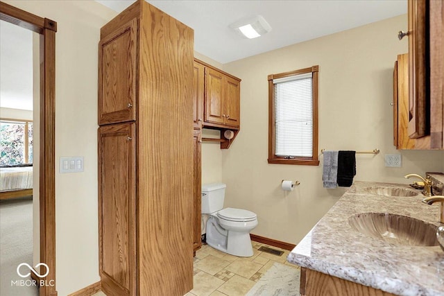 bathroom featuring a sink, baseboards, toilet, and visible vents