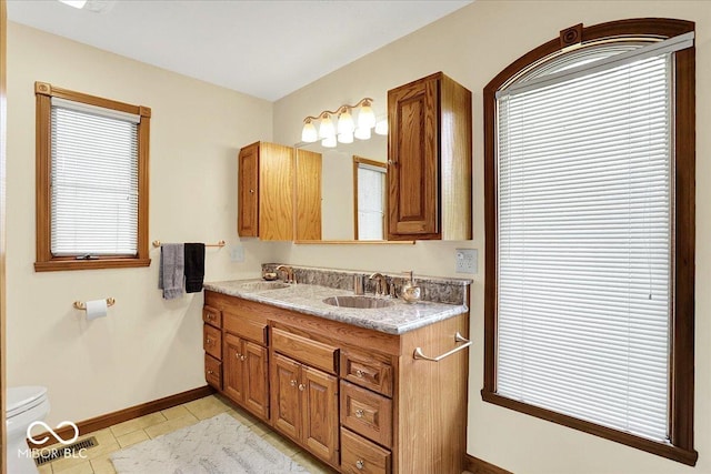 bathroom with double vanity, baseboards, a sink, and tile patterned flooring