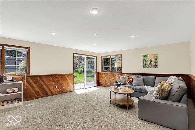 living area with carpet flooring, wood walls, a healthy amount of sunlight, and a wainscoted wall