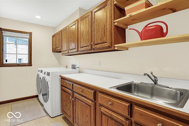 clothes washing area featuring baseboards, recessed lighting, washing machine and clothes dryer, a sink, and cabinet space