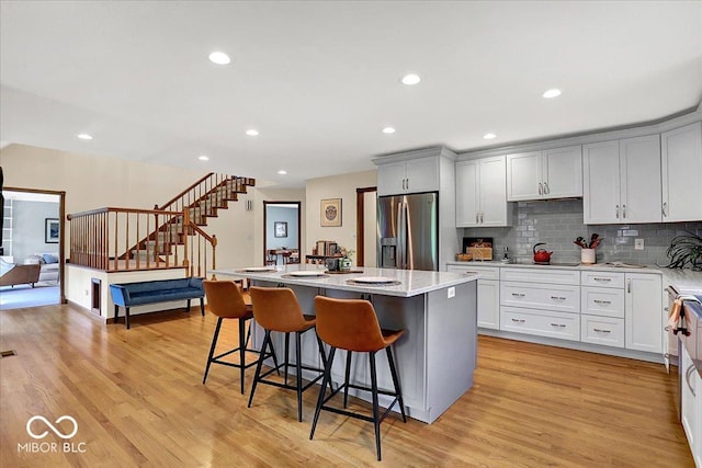 kitchen featuring stainless steel fridge, a kitchen breakfast bar, a kitchen island, and light wood-type flooring