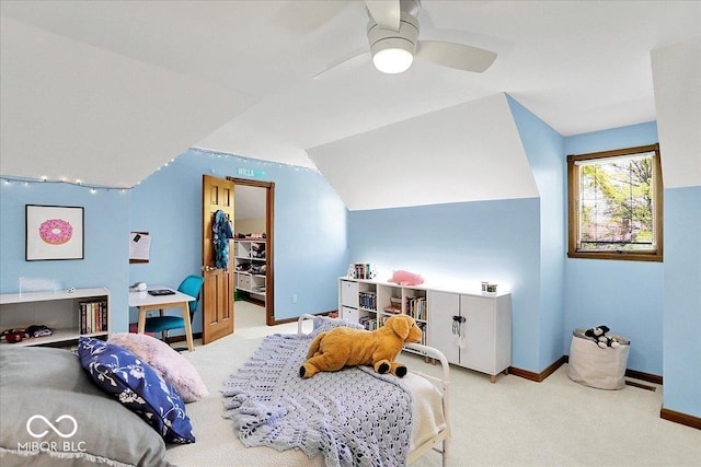 carpeted bedroom featuring a ceiling fan, baseboards, and a walk in closet
