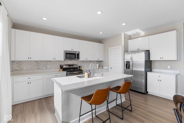8673 Laurelton Pl, Brownsburg, IN 46112 - kitchen with light wood finished floors, stainless steel appliances, white cabinets, a sink, and backsplash