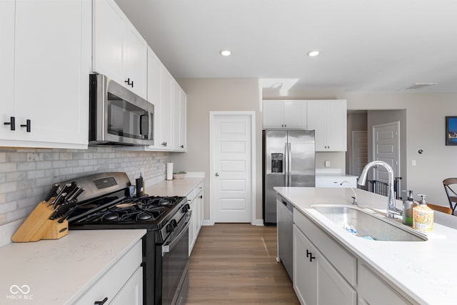 8673 Laurelton Pl, Brownsburg, IN 46112 - kitchen featuring stainless steel appliances, a sink, tasteful backsplash, white cabinetry, and wood finished floors