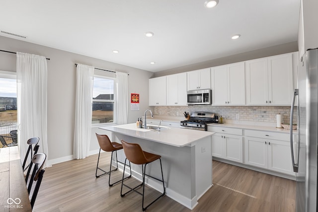 8673 Laurelton Pl, Brownsburg, IN 46112 - kitchen featuring light wood-style flooring, a sink, appliances with stainless steel finishes, and tasteful backsplash