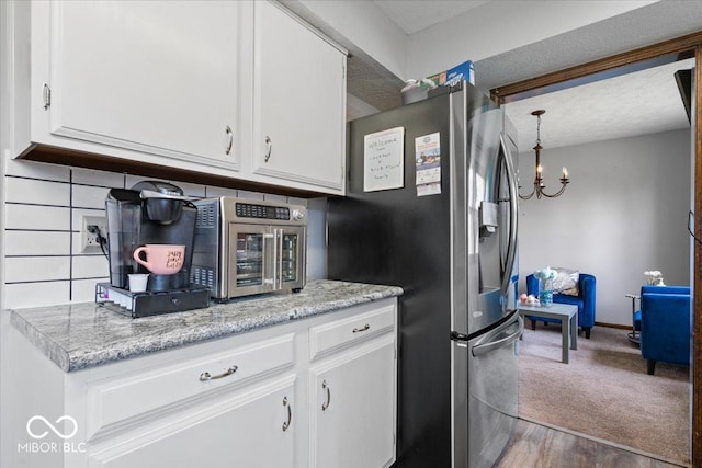 kitchen featuring white cabinets, an inviting chandelier, stainless steel fridge with ice dispenser, light countertops, and backsplash