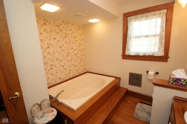 full bathroom with baseboards, a tub with jets, visible vents, and wood finished floors