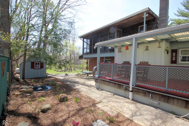 exterior space with a chimney, a shed, an outdoor structure, and a patio