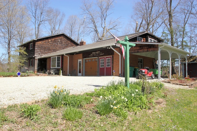 view of front of property featuring brick siding, driveway, a garage, a carport, and a chimney