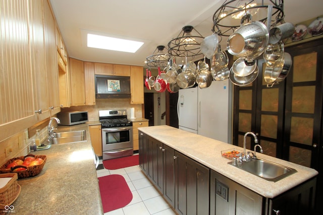 kitchen featuring a sink, freestanding refrigerator, decorative backsplash, and gas range