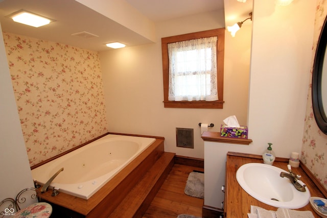 full bathroom with a tub with jets, vanity, and hardwood / wood-style flooring