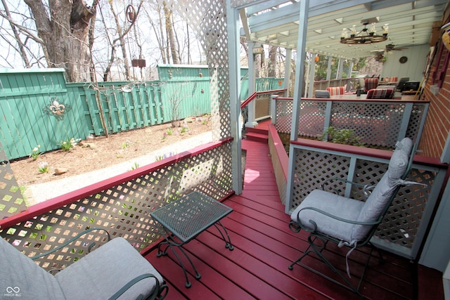 wooden deck featuring ceiling fan, outdoor lounge area, and a fenced backyard