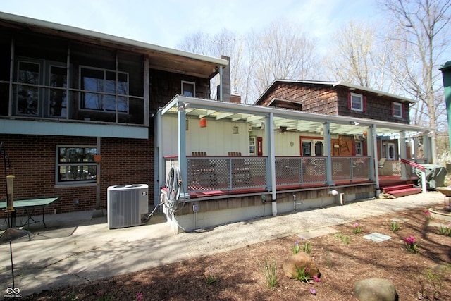 back of house featuring central AC unit, a patio area, a porch, and brick siding