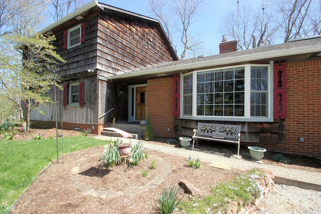 view of front facade featuring brick siding and a chimney