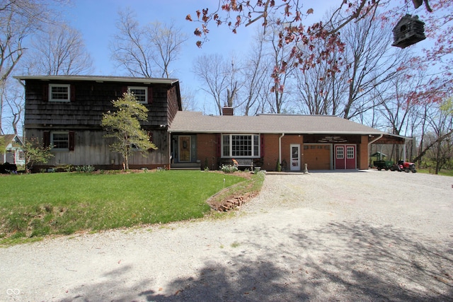 view of front facade with an attached garage, a chimney, a front lawn, brick siding, and driveway