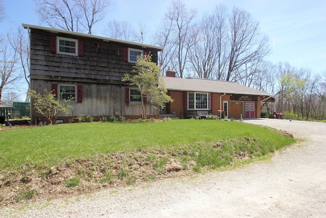 view of front of property with driveway, a chimney, and a front yard
