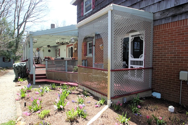 view of side of property with a deck, a ceiling fan, and brick siding