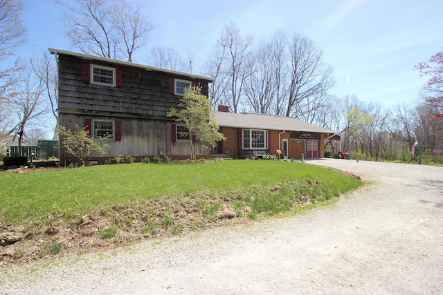 view of front facade with a chimney, dirt driveway, and a front yard