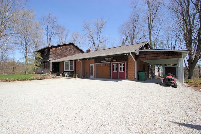 exterior space featuring a chimney, gravel driveway, brick siding, and a garage