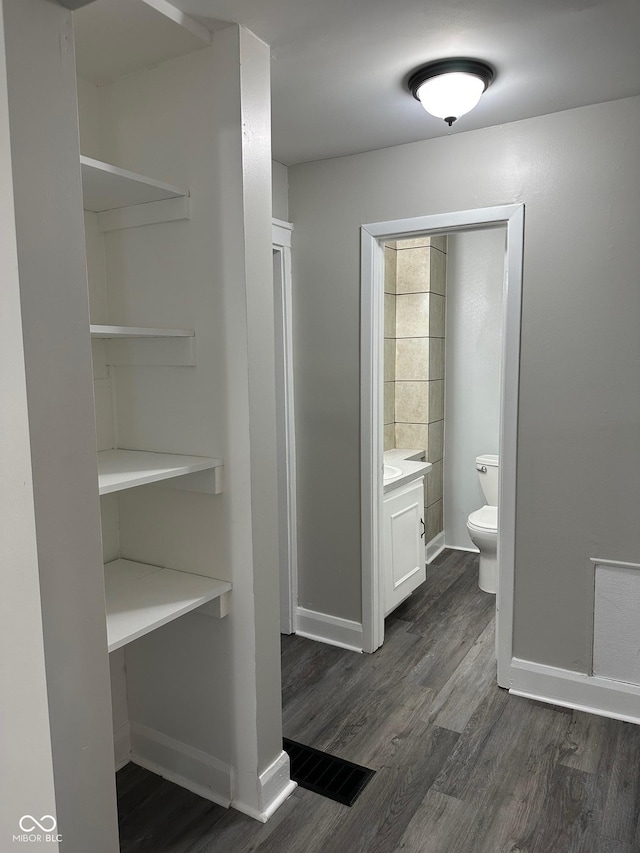 bathroom featuring wood finished floors, visible vents, toilet, vanity, and baseboards
