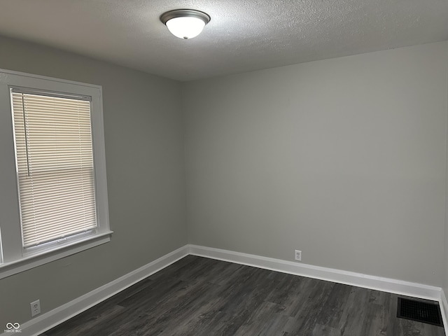 spare room with baseboards, visible vents, and dark wood-type flooring