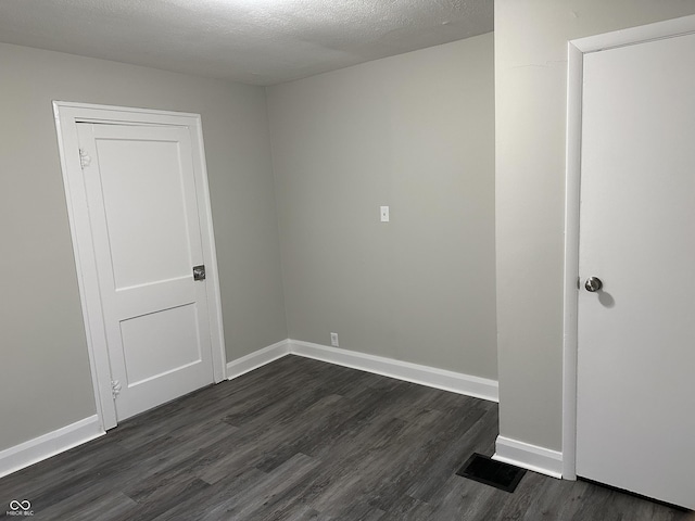 empty room featuring baseboards, visible vents, and dark wood-style flooring