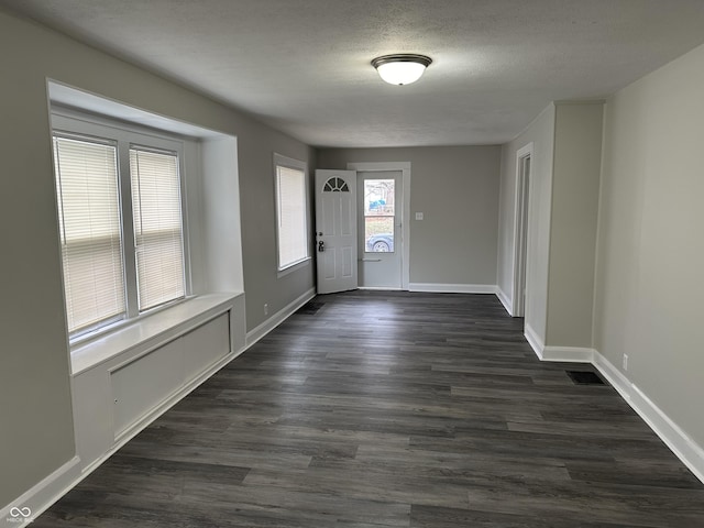 entrance foyer with visible vents, baseboards, a textured ceiling, and dark wood-type flooring