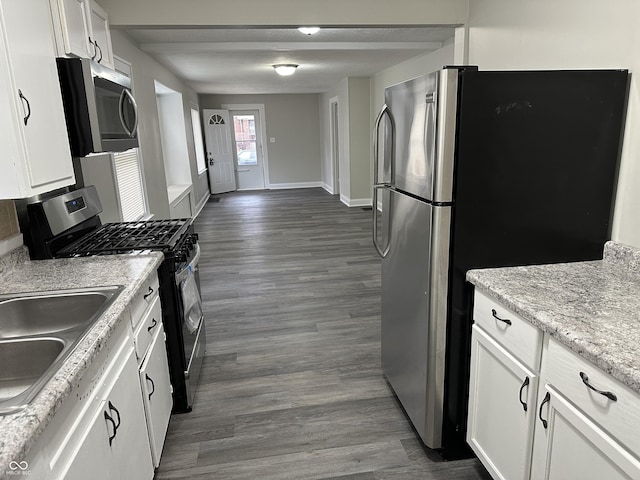 kitchen featuring white cabinets, dark wood-style floors, a sink, baseboards, and appliances with stainless steel finishes