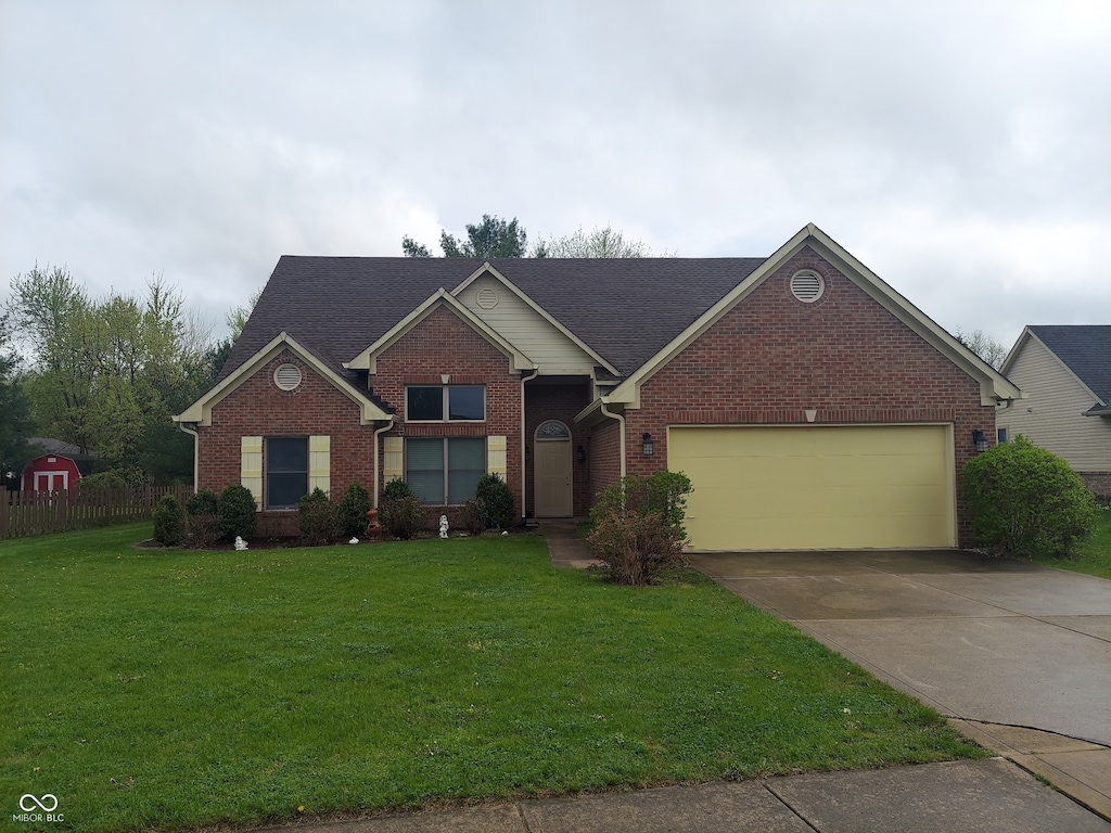 view of front of property with an attached garage, a front lawn, driveway, and brick siding