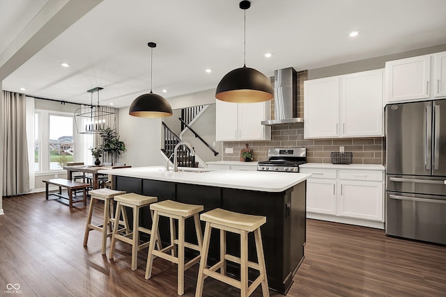 132 Oakhurst Way, Westfield, IN 46074 - kitchen featuring an island with sink, light countertops, wall chimney exhaust hood, appliances with stainless steel finishes, and backsplash