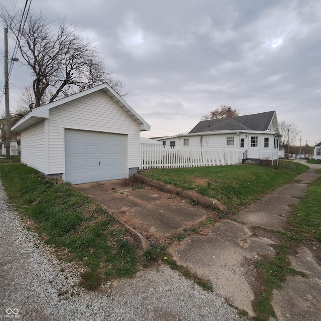 view of home's exterior with an outbuilding, driveway, fence, and a detached garage