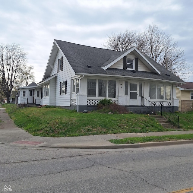 view of front of house with a front lawn and a shingled roof