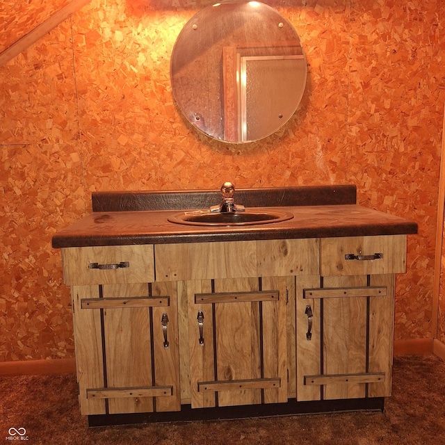 bathroom featuring a sink, baseboards, and wallpapered walls