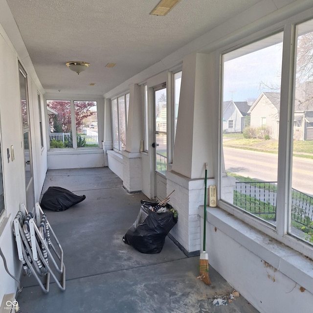 unfurnished sunroom with a textured ceiling and concrete flooring