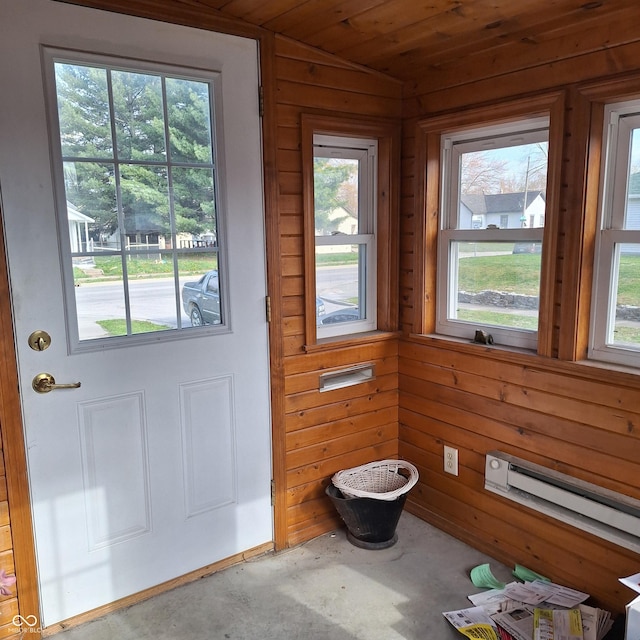 doorway to outside featuring wood walls, a wealth of natural light, and unfinished concrete flooring