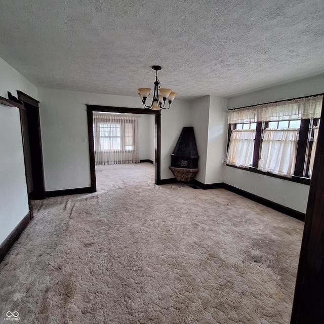 unfurnished living room with a wealth of natural light, a notable chandelier, and carpet flooring