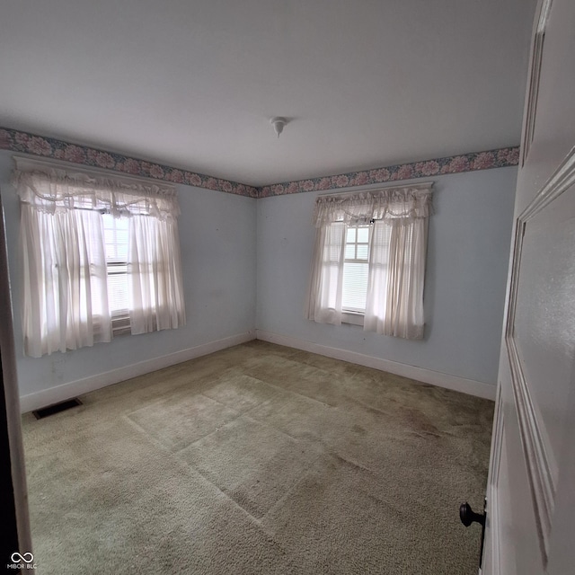 unfurnished room with light colored carpet, visible vents, and baseboards