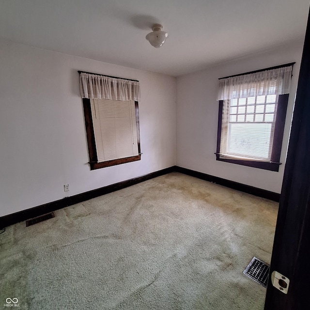 carpeted empty room featuring visible vents and baseboards