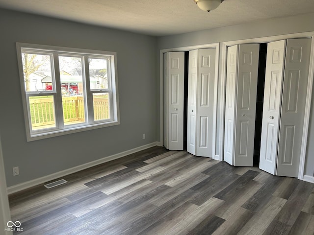 103 N Nebraska St, North Salem, IN 46165 - unfurnished bedroom featuring two closets, baseboards, dark wood-style flooring, and visible vents