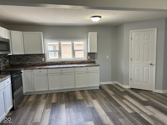 103 N Nebraska St, North Salem, IN 46165 - kitchen featuring dark countertops, stainless steel microwave, decorative backsplash, black range with electric cooktop, and white cabinetry